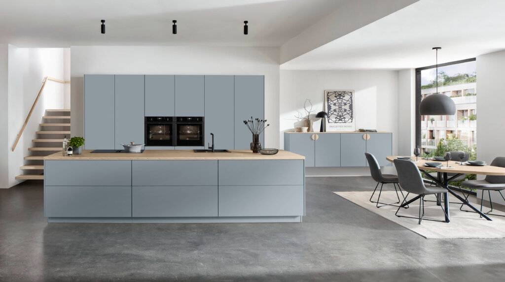 Cocina moderna en Alicante con muebles azul claro, isla central con encimera de madera, comedor integrado y diseño minimalista luminoso.